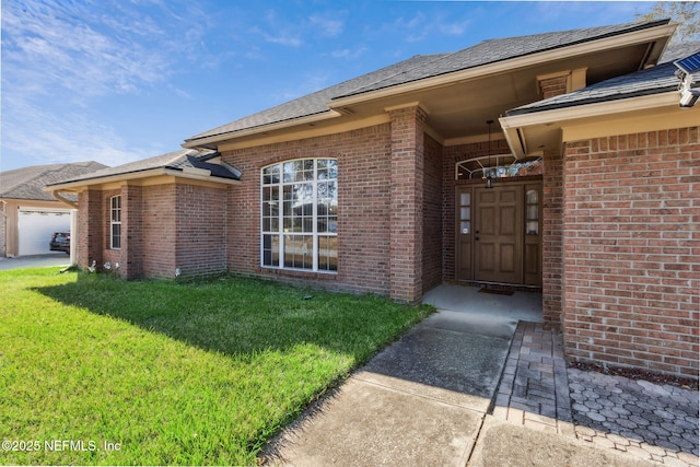 entrance to property with a garage and a lawn