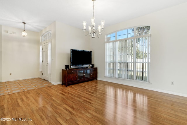 unfurnished living room with light hardwood / wood-style flooring and a notable chandelier