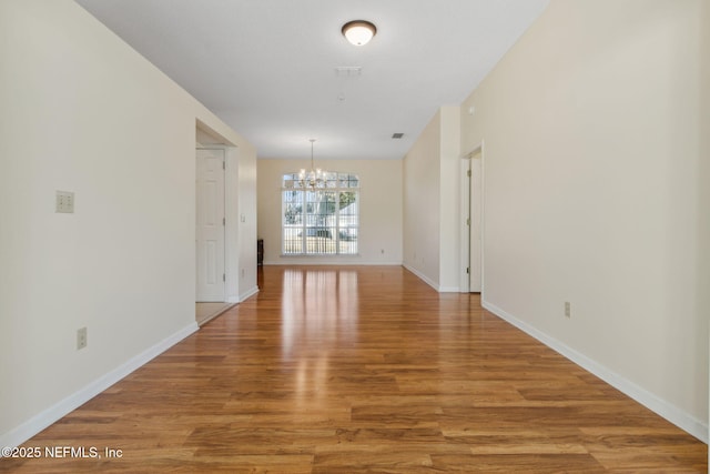 spare room with wood-type flooring and a chandelier