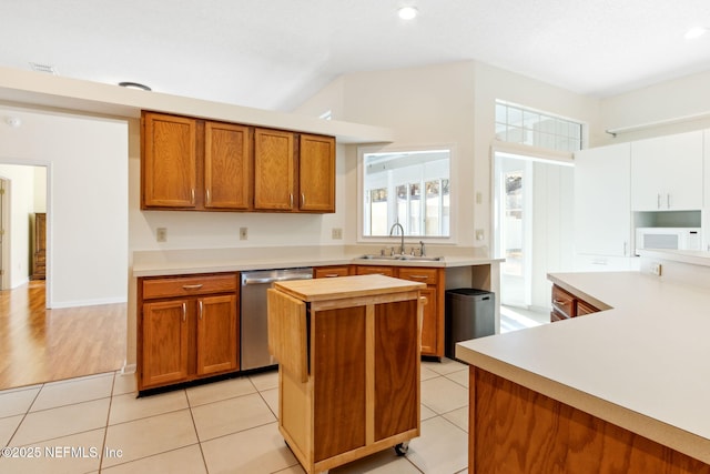 kitchen with sink, stainless steel dishwasher, a center island, and light tile patterned flooring