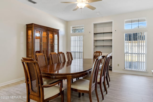 dining area with light hardwood / wood-style flooring, built in features, and ceiling fan