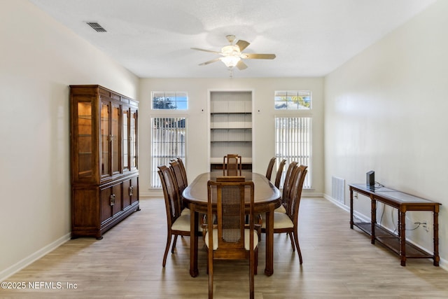 dining space with built in features, a healthy amount of sunlight, and light wood-type flooring