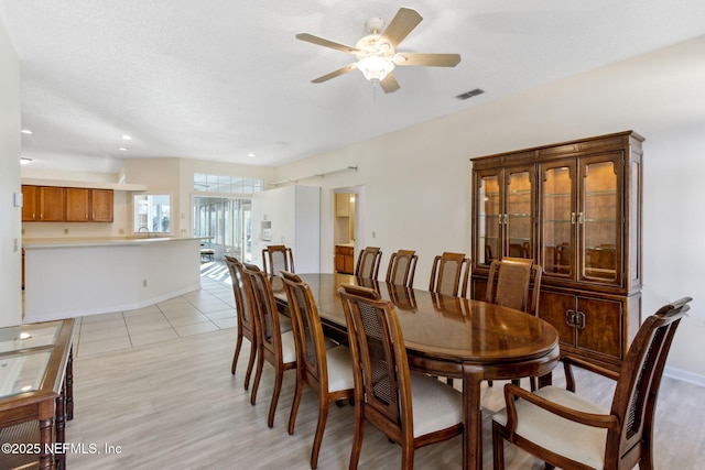 dining room with ceiling fan, a textured ceiling, and light hardwood / wood-style flooring