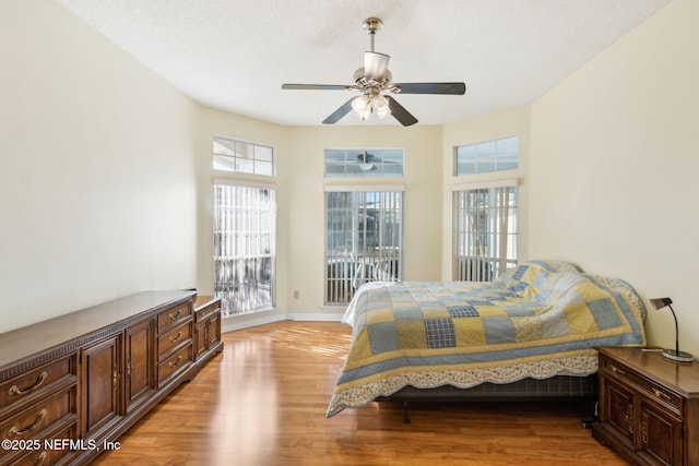 bedroom featuring multiple windows, light hardwood / wood-style floors, and ceiling fan