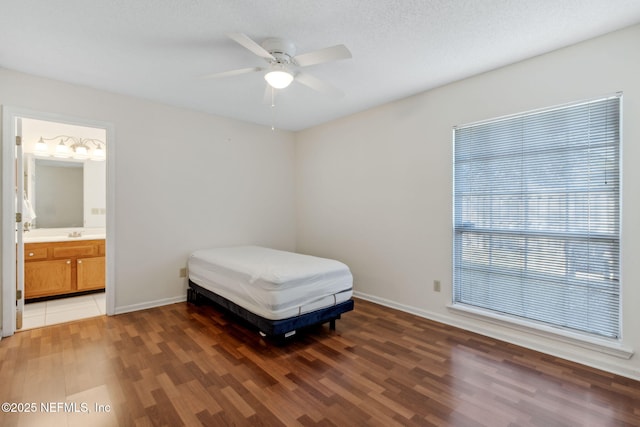 bedroom with sink, ensuite bath, ceiling fan, dark hardwood / wood-style floors, and a textured ceiling