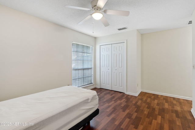 bedroom featuring dark hardwood / wood-style flooring, ceiling fan, a closet, and a textured ceiling