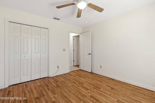 unfurnished bedroom with ceiling fan, light hardwood / wood-style floors, a closet, and a textured ceiling