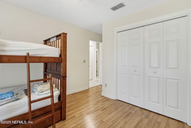 bedroom featuring light hardwood / wood-style floors, a closet, and a textured ceiling