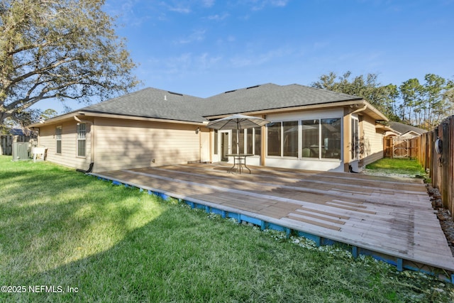 back of house with a wooden deck, a sunroom, and a lawn