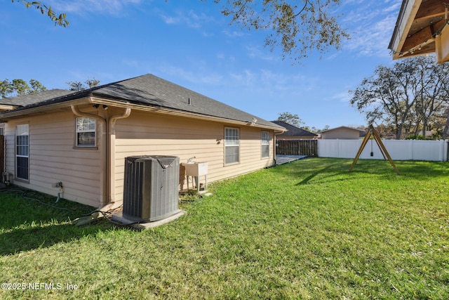 rear view of property featuring sink, a yard, and central AC