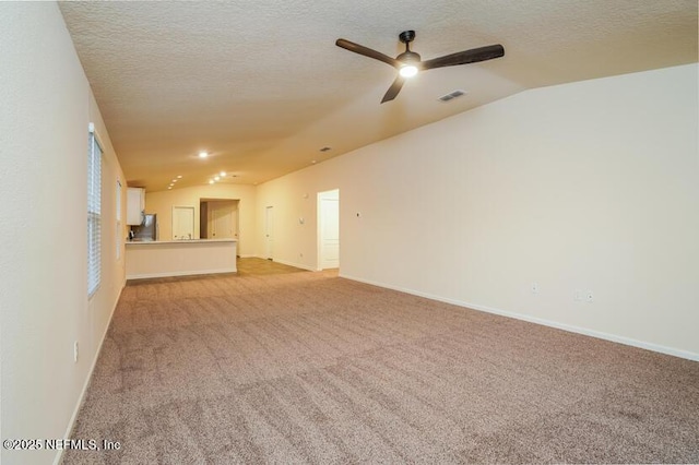 unfurnished living room with ceiling fan, vaulted ceiling, light colored carpet, and a textured ceiling