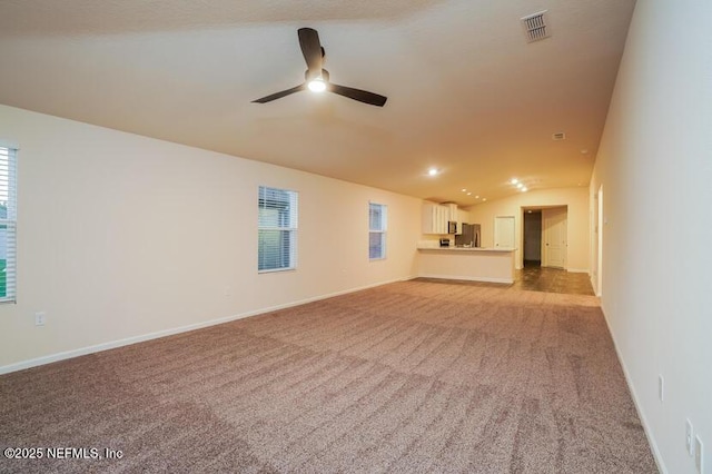 unfurnished living room with ceiling fan, light colored carpet, and vaulted ceiling