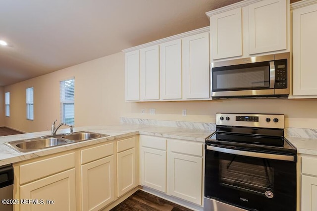 kitchen with sink, white cabinetry, dark hardwood / wood-style floors, kitchen peninsula, and stainless steel appliances