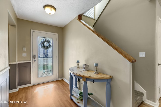 foyer featuring hardwood / wood-style floors, a skylight, and a textured ceiling