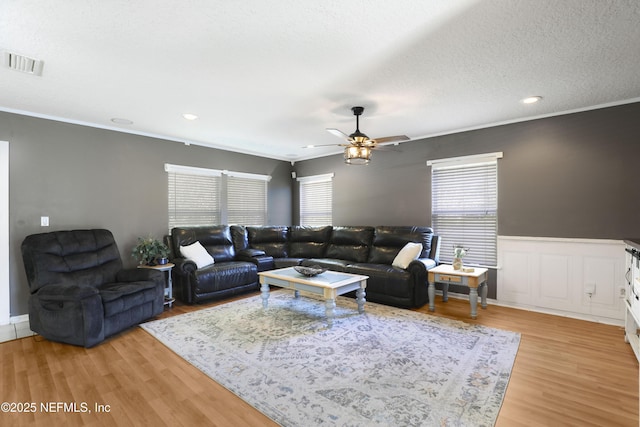 living room with crown molding, ceiling fan, light hardwood / wood-style floors, and a textured ceiling