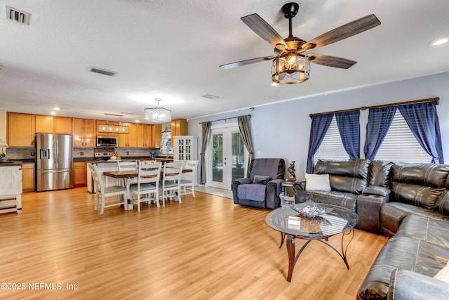 living room with french doors, ceiling fan, a textured ceiling, and light wood-type flooring