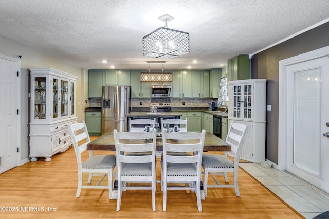 dining area with sink, a textured ceiling, an inviting chandelier, and light hardwood / wood-style floors