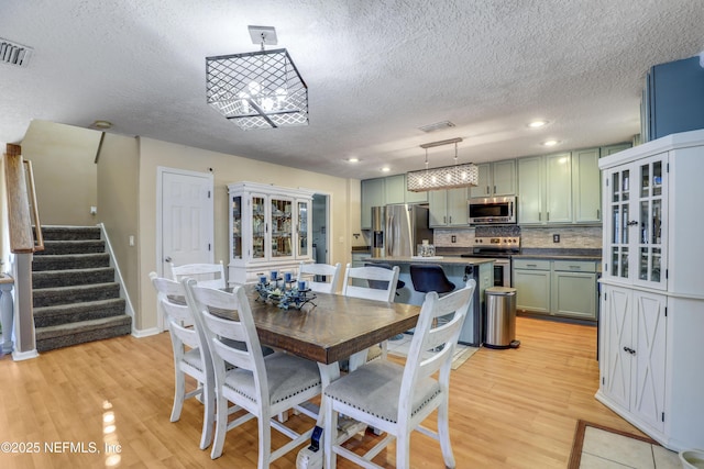 dining space with light wood-type flooring and a textured ceiling