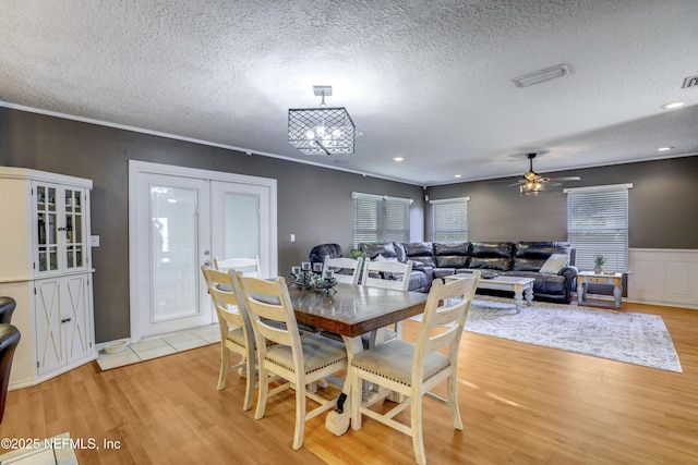 dining area featuring ceiling fan, light hardwood / wood-style floors, french doors, and a textured ceiling