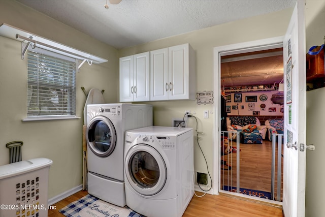 laundry room featuring cabinets, washing machine and dryer, a textured ceiling, and light hardwood / wood-style floors