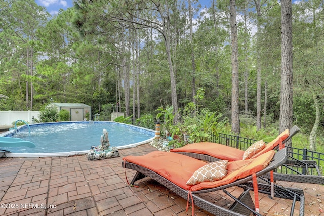 view of pool with a storage shed and a patio