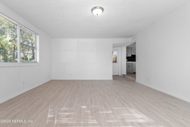 unfurnished room with a textured ceiling and light hardwood / wood-style floors