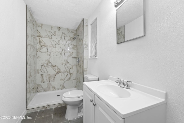 bathroom with tile patterned flooring, tiled shower, vanity, a textured ceiling, and toilet