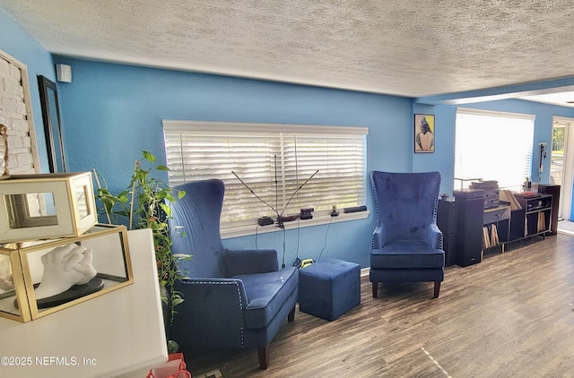 sitting room with a textured ceiling, a textured wall, and wood finished floors