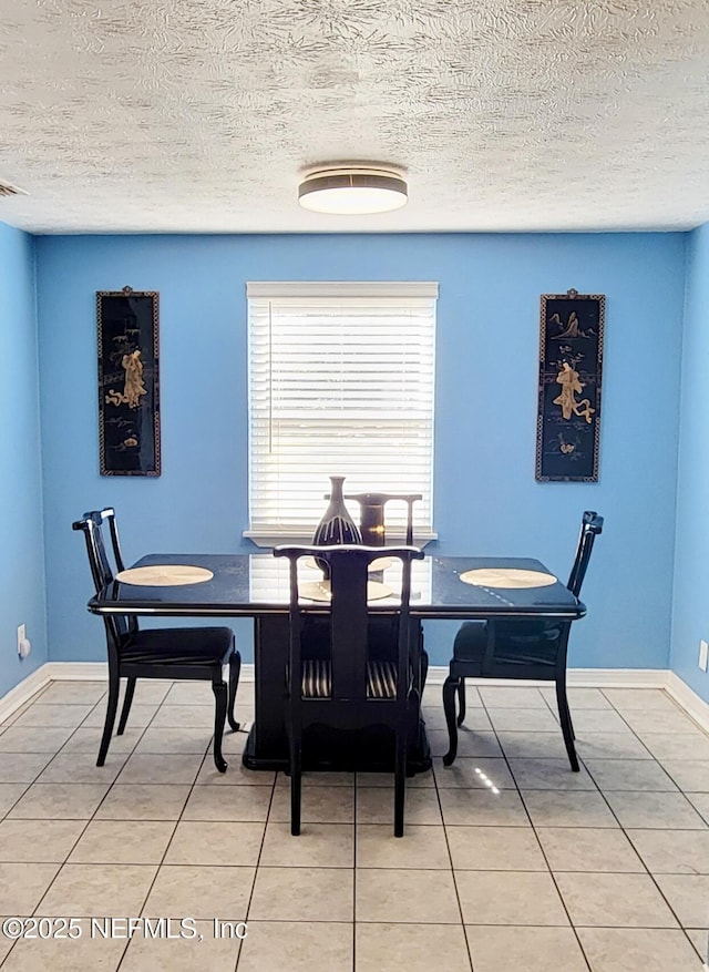 tiled dining area featuring a textured ceiling