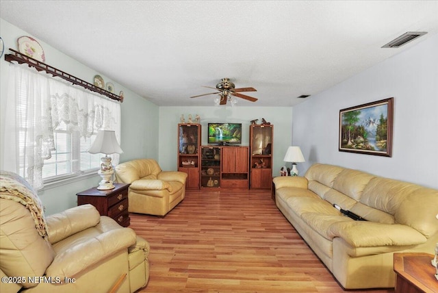 living room with ceiling fan, light hardwood / wood-style floors, and a textured ceiling