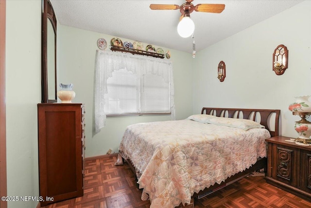 bedroom with dark parquet flooring, ceiling fan, and a textured ceiling