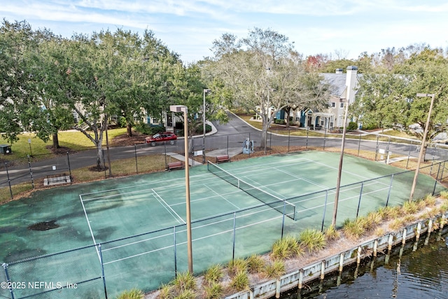 view of tennis court with a water view