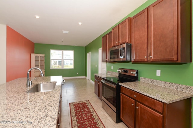 kitchen featuring light tile patterned flooring, appliances with stainless steel finishes, sink, and light stone counters