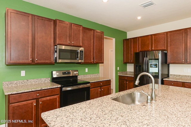 kitchen with sink, stainless steel appliances, and light stone countertops