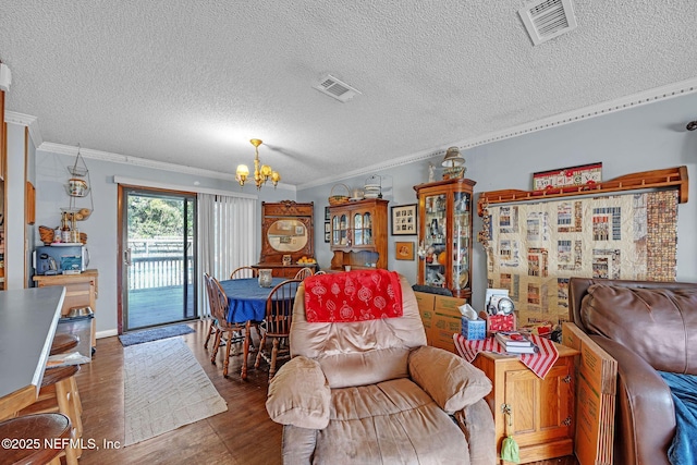 living room featuring ornamental molding, dark hardwood / wood-style floors, a textured ceiling, and a notable chandelier