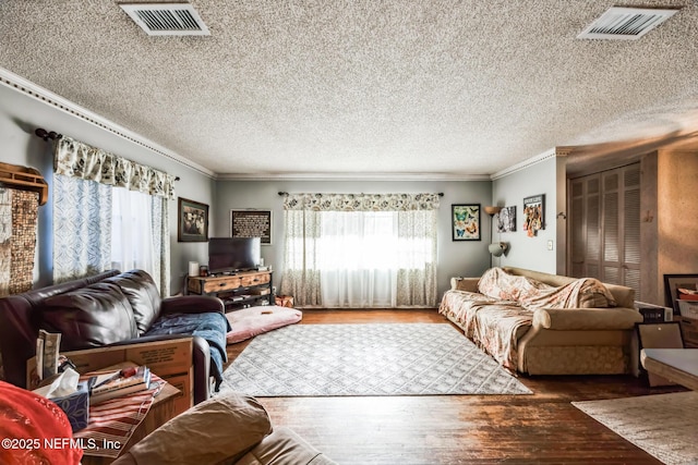 living room featuring dark wood-type flooring, ornamental molding, and a textured ceiling