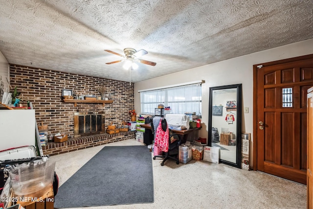 living room with a brick fireplace, brick wall, a textured ceiling, and ceiling fan