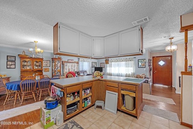 kitchen with light tile patterned flooring, decorative light fixtures, ornamental molding, a notable chandelier, and white cabinets