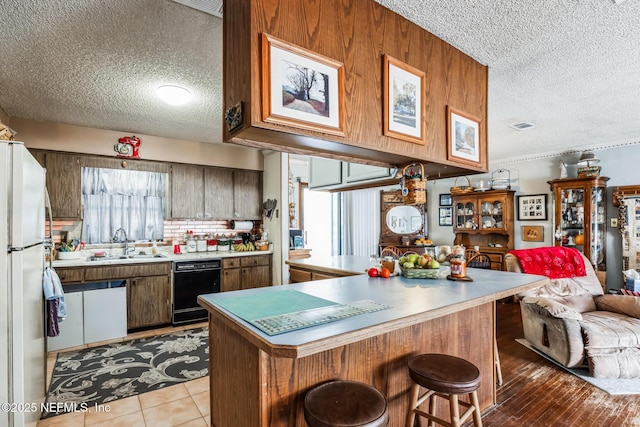 kitchen with refrigerator, tasteful backsplash, sink, a breakfast bar area, and kitchen peninsula