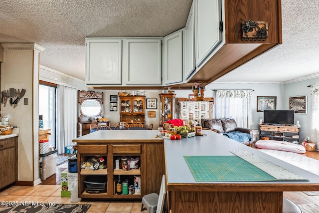 kitchen with a textured ceiling, ornamental molding, a healthy amount of sunlight, and light tile patterned flooring