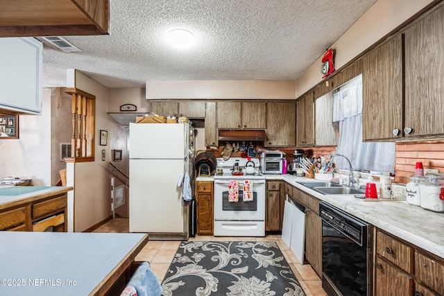 kitchen featuring sink, white appliances, a textured ceiling, and light tile patterned flooring