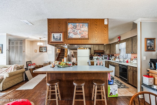 kitchen with white appliances, a kitchen bar, sink, and a textured ceiling