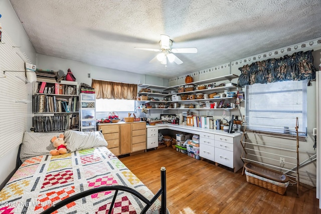 interior space with ceiling fan, wood-type flooring, and a textured ceiling