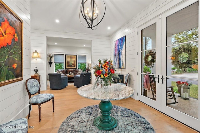 dining room with wood-type flooring, a notable chandelier, wooden walls, and french doors