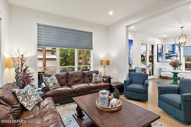 living room featuring an inviting chandelier, light hardwood / wood-style flooring, and french doors