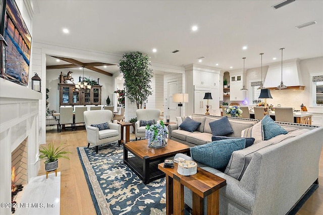 living room featuring ornamental molding, light hardwood / wood-style floors, a premium fireplace, and a chandelier