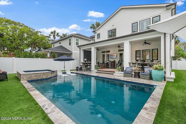 back of property with a swimming pool with hot tub, a patio area, ceiling fan, and a lawn