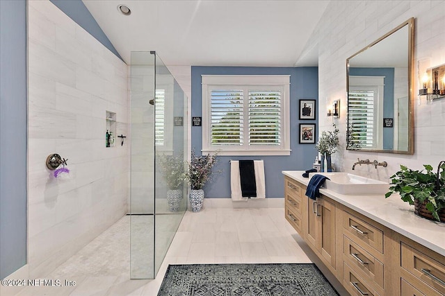 bathroom with vanity, vaulted ceiling, and tiled shower