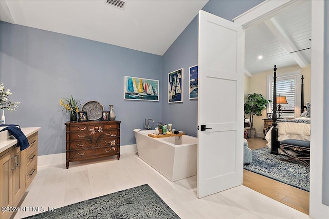 bathroom with vanity, vaulted ceiling with beams, and a washtub