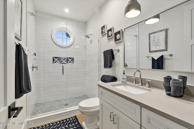 bathroom with vanity, a shower with door, and toilet